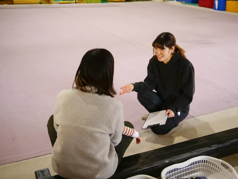 コーチと話しながら体操を体験する子ども